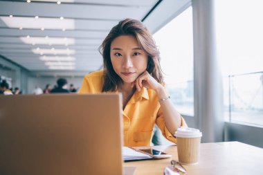 Modern netbook cihazıyla çekici bir kadın blogcunun portresi öğrenme molasında kameraya bakıyor, Çinli kız öğrenci bilgisayarın çalışma alanında uzaktan çalışıyor.