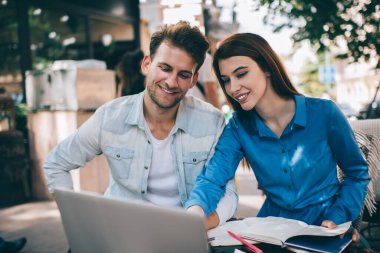 Kafenin terasında oturan yakışıklı adamla sohbet ederken dizüstü bilgisayarı olan gülümseyen akıllı kadın.