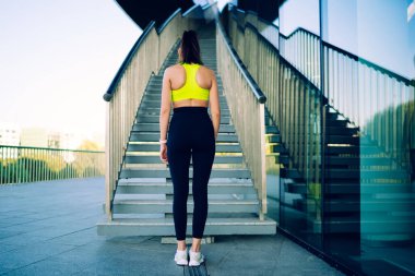 Aktif haldeki kadın koşucunun arkadan görünüşü merdivenlerin yanında durup aktif eğitime hazırlanmak sağlıklı yaşam tarzını korumak için mükemmel vücut şekli ve motivasyon hedefleri olan beyaz kadın.