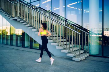 Şehir merkezinde kardiyo eğitimi alan atletik yapılı kadın vücut geliştirici, şehirde dayanıklılık egzersizi yapmaktan hoşlanan kaslı bir kadın aktif sporla sağlıklı yaşam tarzı uyguluyor.