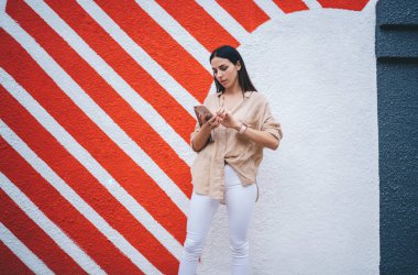 Kafkasya milenyumu akıllı telefondan internet sitesinde taşınabilirlik rezervasyonu yapmak için 4G 'ye bağlanıyor, güzel kız tanıtım alanında duran içerik metinlerini okumak için cep telefonu aygıtı kullanıyor