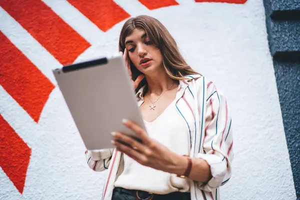 Caucasian female puzzled with received email message on modern touch pad solving problems with web delivery service, young woman reading news on browsed website connected to 4g on digital gadget