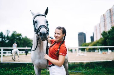 Beyaz atlı kızın yarım boy portresi doğadaki binicilik yarışması sırasında poz veren kadın binici hobi sırasında kameraya gülümseyen beyaz atlı aygır hayvanı
