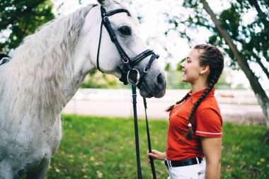 Mutlu Kafkas jokeyi, dost canlısı itaatkar ata bakıyor ve gülümsüyor. Golf kulübünde vakit geçirmenin keyfini çıkarıyor. Esmer saçlı kaygısız kız safkan aygırla iletişim kuruyor.