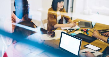 Yukarıdan bakıldığında, Afrika kökenli Amerikalı bir erkeğin, çeşitli iş arkadaşlarıyla masaya oturmuş, not defterine yazı yazarak proje üzerinde birlikte çalışmasını görüyoruz.