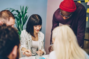 Gündelik giysiler içinde çok ırklı iş arkadaşları, güncel iş yerinde toplanırken belge okuyup iş stratejisi düşünürler.