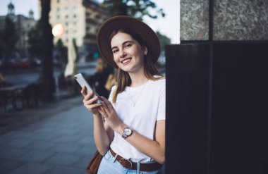 Sosyal ağlarda sohbet etmek için cep telefonunu kullanan şık şapkalı neşeli beyaz kadın portresi. Milenyum hücresi tutan mutlu yeniyetme kız.