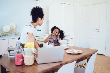 İyi ki siyah çocuk gülümseyip ebeveyne bakarken kıvırcık anne masanın önünde şeker ve malzemelerle duruyor.