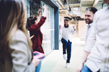 Modern ofis binasının koridorunda iş ortağıyla başarılı müzakereleri kutlayan kısmen isimsiz bir grup heyecanlı ofis çalışanı.