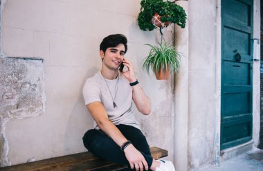 Yakışıklı beyaz erkek portresi şık günlük kıyafetlerle boş zamanlarında pozitif sohbetin tadını çıkarıyor, 20li yaşlarda hipster bir adam cep telefonu için ucuz tarifeler kullanarak kameraya bakıyor.