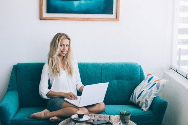 Mutlu Kafkasyalı kadın hizmetçi modern dizüstü bilgisayarla online ağ kurma haftasonu tatilinin keyfini çıkarıyor. Tasasız milenyum kızı netbook teknolojisi ve gülümseme ile rahat bir koltukta oturuyor.
