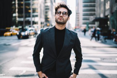 Görüş düzeltmesi için optik gözlük takan düşünceli erkek girişimci şehir merkezindeki finans bölgesinde durup düşünceli, takım elbiseli Avrupalı iş adamı