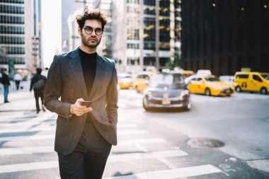 Klasik gözlüklü düşünceli bir adam modern cep telefonu teknolojisi üzerine iş yayınından gelen içerik metni üzerinde kafa yoruyor. Finans bölgesinde akıllı telefon kullanan genç Avrupalı erkek yönetmen.