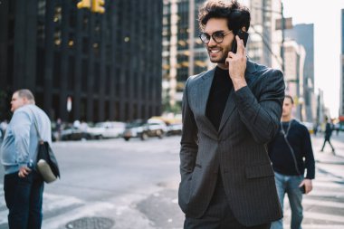 Manhattan şehir merkezinde yürürken akıllı telefondan konuşan mutlu genç işadamı, resmi giyinmiş başarılı bankacı ve cep telefonu teknolojisiyle iletişim kuran gözlük