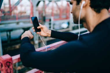 Milenyum adamı cep telefonundan gelen mesajı açık havada çalışırken 4G bağlantısını kullanarak okuyor, aktif erkek koşucu, akıllı telefondan motifli çalıştırmak için çalma listesindeki şarkıları kontrol ediyor.