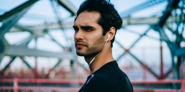 Düşünceli erkek koşucu dışarıda koşmaya başlamadan önce kardiyo egzersizleri ve sağlıklı yaşam tarzını düşünüyor. Kaslı vücutlu düşünceli bir adam spor sonrası kulaklıkla müzik dinliyor.