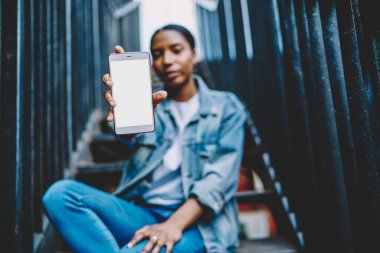 İnternet sitesi ya da metin reklamları için kopyalama alanı olan modern akıllı telefon teknolojisine seçici odaklanma, boş ekranlı cep telefonu aygıtı gösteren Afrikalı Amerikalı etki blogcusu