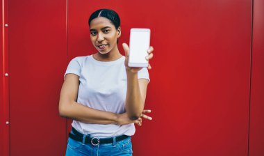 Terfi reklamları sırasında ekranı taklit ederek akıllı telefon kullanan çekici, esmer bir kadının yarım boy portresi. Fotokopi alanı olan tişört giymiş genç blogcu cep telefonunu gösteriyor.