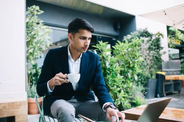 Zengin iş adamı 20 'li yaşlarda moda kıyafetleri içinde internetten kahve fincanı tutan videolar izliyor, ciddi bir erkek milenyum girişimcisi haberleri okuyor ve kafeterya terasında postaları kontrol ediyor.