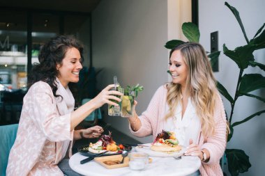 Kafkas kadın esmer ve sarışın en iyi arkadaşlar kafeteryada soğuk kokteyllerle buluşmayı kutluyorlar, 20 'li yaşlarda sağlıklı yemek yiyen ve öğle yemeği molasında içeceklerle sohbet eden kadınlar.