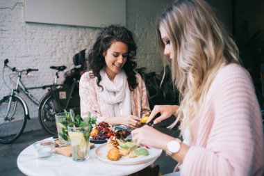 Gülümseyen beyaz kadın meslektaşlar akşam yemeğinde birlikte vakit geçiriyorlar sağlıklı yemekler yiyor ve birbirleriyle konuşuyorlar, 20 'li yaşlarda pozitif kadınlar öğle tatili ve lezzetli yemekler yiyorlar.