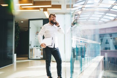 Neşeli, müreffeh, beyaz erkek yönetici cep telefonu görüşmeleri sırasında gülümsüyor, başarılı gururlu CEO, şık günlük kıyafetler giyiyor akıllı telefon görüşmeleri yapıyor ofiste proje için iyi fikirler paylaşıyor.