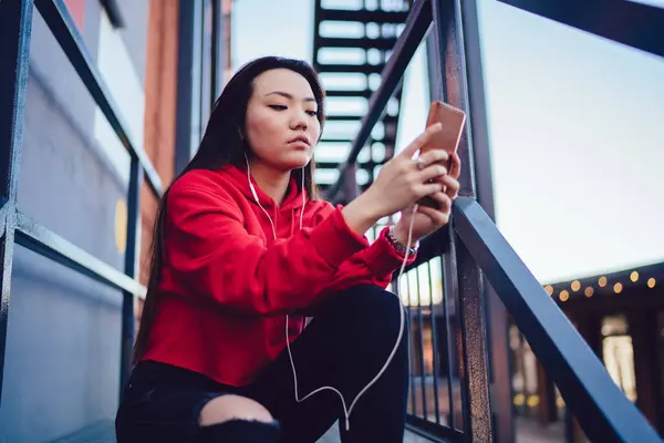 千禧年的日本女性通过智能手机的媒体应用搜索流行歌曲 以获得闲暇时间 在耳机信息和在网站上选择有声书籍方面具有吸引力的亚洲一代Z — 图库照片