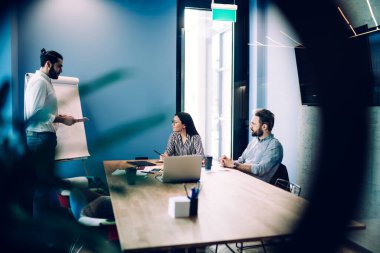 Proje üzerinde çalışırken ve ofis odasında otururken iş fikirlerini paylaşan ve tartışan kendine güvenen bir grup iş arkadaşının penceresinden bakın