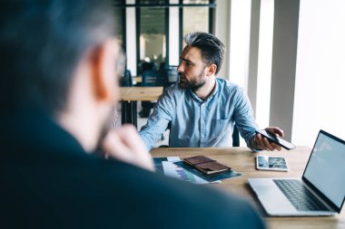 Hüsrana uğramış erkek yönetici masada oturuyor ve iş arkadaşlarıyla aynı fikirde değilken ellerini açıyor ve iş toplantısı sırasında bakış açısında ısrar ediyor. 