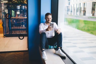 Neşeli erkek nüfuzlu kişi, modern cep telefonu cihazında 4G kablosuz bağlantısı olan sosyal takipçilerle iletişim kurmak için internet üzerinden sohbet ediyor. Klasik göz giysisi giyen mutlu genç adam video aramasından hoşlanıyor.