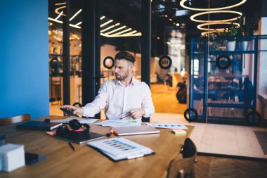 Modern çalışma alanındaki belgelerle uzaktan muhasebe sırasında modern akıllı telefon cihazını kontrol eden Kafkas erkek çalışanı genç işadamına cep telefonu uyarısı geldi.