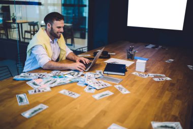 Başarılı erkek milyoner internet piyangosunu kontrol ederek modern dizüstü bilgisayarda internete kablosuz erişimle sonuçlandı. Neşeli adam ofiste boş monitörle çalışarak kar elde etti.