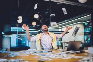 Neşeli eğlence sektörü yatırımcısı online hisse senedi platformunda iyi para değiş tokuşundan memnun, temettü kazanan heyecanlı bir adam piyango kazanmasıyla sevinçten havalara uçuyor.