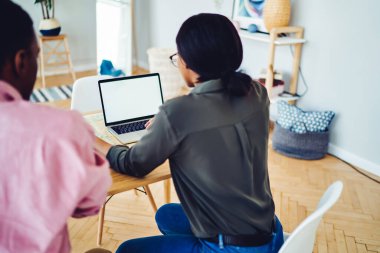 Yukarıdan bakıldığında, aydınlatma odasındaki masada otururken laptopta boş ekranla çalışan çok ırklı bireyler görülüyor.