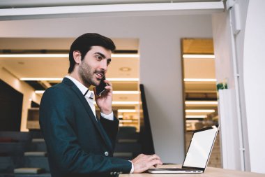 Resmi olarak Hintli işadamı masaüstünde internet reklamları için dizüstü bilgisayarla oturuyor ve akıllı telefon aracılığıyla iş konuşmaları yapıyor. Cep telefonuyla finansal uzman arıyor.