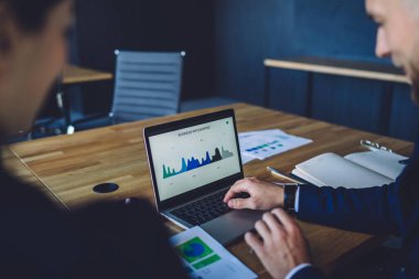 Profesyonel uzmanların strateji verimliliğini tartışmak için dizüstü bilgisayardaki ticari kazanç bilgilerine göz attıkları kırpılmış görüntü, web grafik grafiklerini netbook uygulaması üzerinden kontrol eden tüccarlar