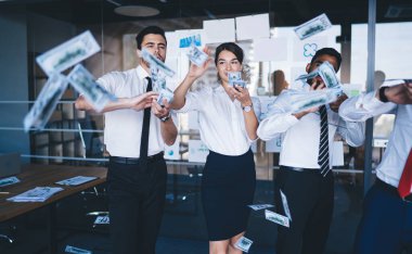 Kendine güvenen ofis çalışanları resmi kıyafetler giyip kurumsal odada dolarlarla ayakta duruyor ve sermaye yatırımının başarısının tadını çıkarıyor para saçıyor, para tahılı kavramını fırlatıyor.