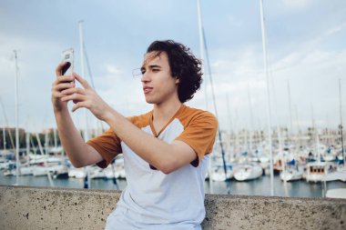 Yaz tatilleri hakkında bilgilendirici video bloğu çeken genç internet etkileyicisi blogcu blog yazarı, internetteki cep telefonu uygulaması üzerinden selfie resimleri yapmak için 4G 'ye bağlanan genç hippi.