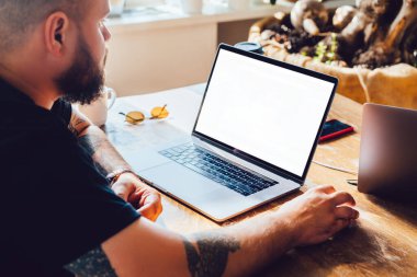 Netbook boş ekran izlerken ve masaüstünde otururken fareyi kullanarak gündelik kıyafetli bir ekin ofisi yöneticisinin yan görünümü