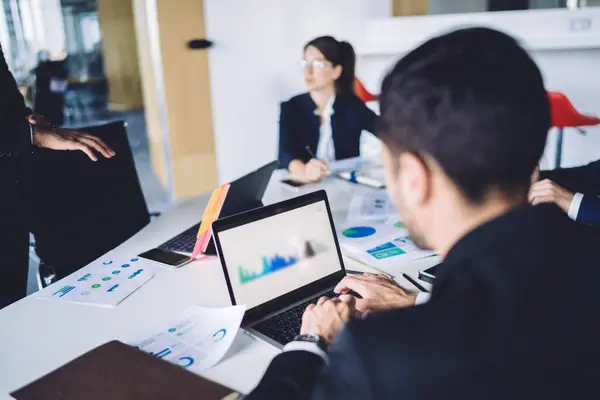 stock image Group of perspective business experts working together in office during meeting, male and female colleagues talking about trade and analyzing financial capital from paper chart infographics