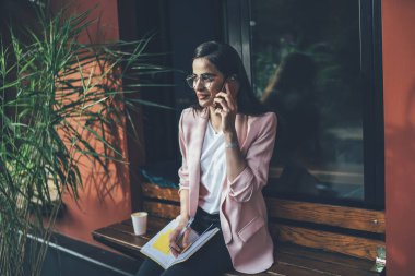 Gürcü kadın şık günlük kıyafetler giyip uluslararası akıllı telefon konuşmaları yaparak kaldırımda organizasyon kuruyor, gözlüklü güzel kız öğrenci mobil uygulama üzerinden arıyor.