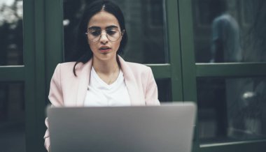 Modern dizüstü bilgisayarda uzak mesafe çalışması yapan yetenekli kadın, klasik gözlüklü bin yıllık kadın çevrimiçi seminer arıyor ya da dijital netbook hakkında bilgi edinmek için özel kıyafet giyiyor.