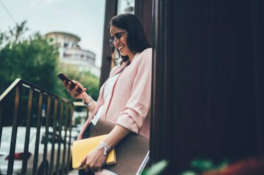 Yeni nesil Z, sosyal ağ kurarken akıllı telefon mesajlarından keyif alıyor. Sayısal cep telefonu aygıtında içerik yayınını paylaşmak için 4G 'yi kullanan gözlüklü samimi bir kadın.