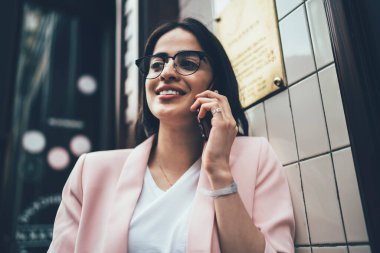 Görme düzeltmesi için optik gözlüklü güzel İspanyol kullanıcı boş zamanlarında uluslararası telefon konuşmalarından keyif alıyor, pozitif iletişim kurmak için aylak aylak dolaşan gözlüklü çekici kadın.