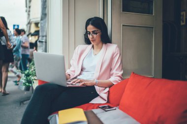 Klasik göz giysisi giyen İspanyol kadın serbest meslek sırasında web içeriği ve grafik tasarımı hakkında bilgi topluyor, kaldırımdaki kablosuz internete bağlanan Webinar videolarını izleyen yetenekli bir kadın.