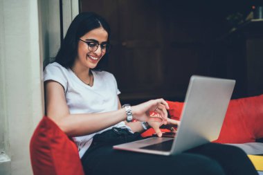 Neşeli İspanyol serbest yazar boş zamanlarında sosyal ağ teknolojisini kullanarak görme düzeltmesi için optik göz giysisinde takılabilir kol saati ve gülümseyen kadın nesli Z 'yi kontrol ediyor.