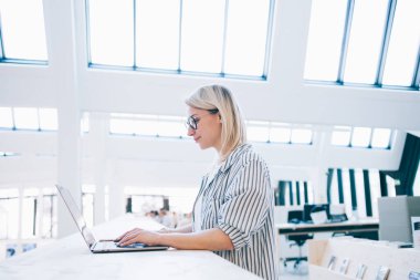 Birlikte çalışma alanında 4G kablosuz bağlantıya bağlı dizüstü bilgisayar sistemi güncellemesi arayan yetenekli kadın yan görünümü, blog web sitesi fikirleri ile uzaktan çalışan genç serbest çalışan