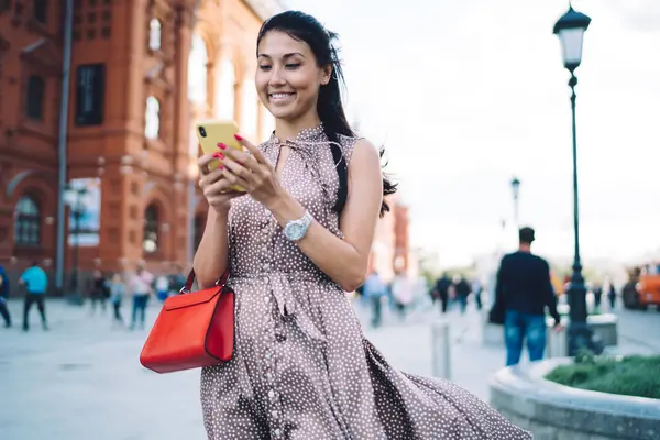 Joyful female tourist using cellular technology for creating content publication with web guide for visiting Moscow city, pretty woman with smartphone reading positive message during online chatting