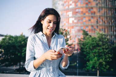 Gülümseyen beyaz kadın turist milenyumu şehir merkezinde duran seyrüsefer uygulamasından memnun, medya indirmek için cep telefonundan indirimli mesaj alan pozitif kadın