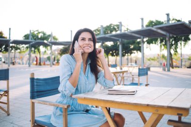 Kafe terasında rahat rahat giyinen güzel, pozitif bir kadın cep telefonu sohbetinin tadını çıkarıyor. 30 'lu yılların kadın milenyumu akıllı telefonla konuşuyor. Sokaktaki bağlantıdan tatmin olmuş bir şekilde dolaşıyorlar.